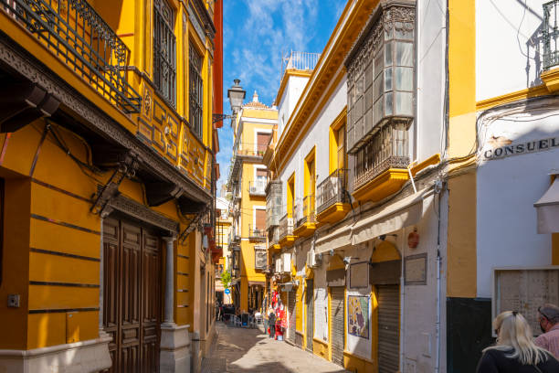 A picturesque street of shops, homes and cafes in the Barrio Santa Cruz district of the Andalusian city of Seville, Spain. A picturesque street of shops, homes and cafes in the Barrio Santa Cruz district of the Andalusian city of Seville, Spain. santa cruz seville stock pictures, royalty-free photos & images