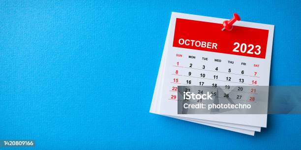 White Sticky Note With 2023 October Calendar And Red Push Pin On Blue Background Stock Photo - Download Image Now