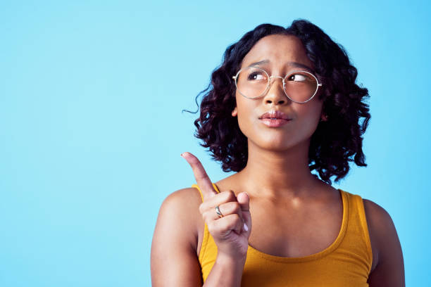 femme confuse, direction pensante et arrière-plan de maquette de studio. personne pensive, agacée ou curieuse qui envisage de prendre une décision. fille avec une solution ou une idée pointant pour la publicité marketing. - en désordre photos et images de collection