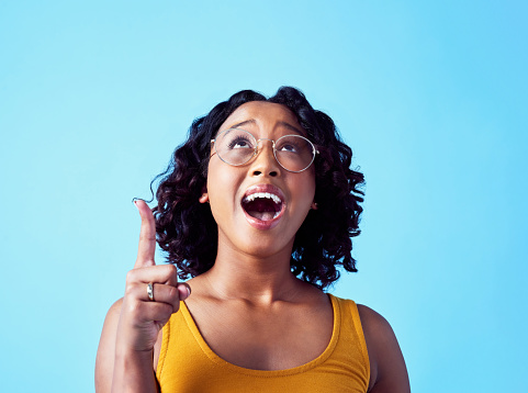 Mockup space, happy and wow woman pointing finger at marketing, advertising and commercial promo offer. Background, surprised and excited lady shocked at announcement, sales and deal in blue studio