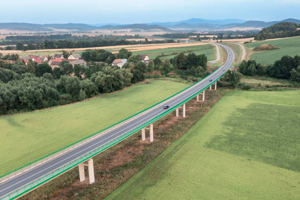 istock Top view of a long bridge passing through green fields 1420817720