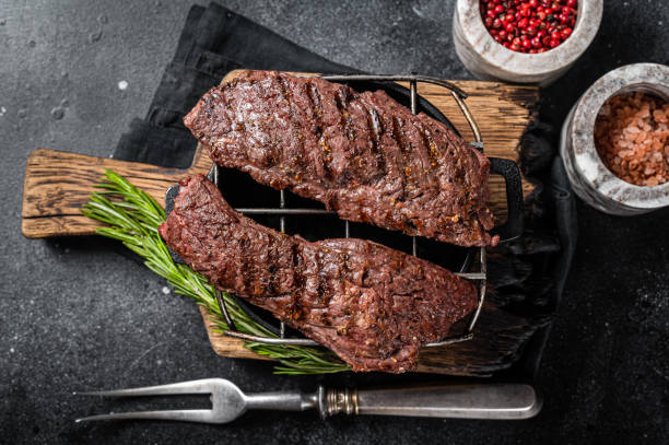 Grilled Machete skirt steak on grill. Black background. Top view Grilled Machete skirt steak on grill. Black background. Top view. beef flank steak stock pictures, royalty-free photos & images