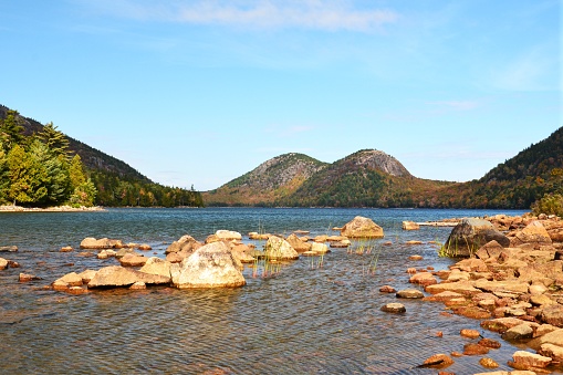 The North and South Bubble Mountains are seen at an autumn sunset from the shoreline of Jordan Pond in Acadia National Park on Mount Desert Island, Maine.
