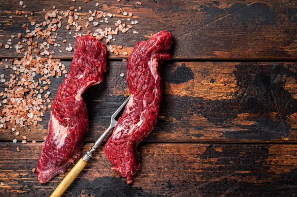 Uncooked raw Machete skirt steak on meat fork. Wooden background. Top view. Copy space