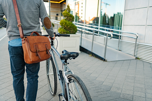 Side view of an unrecognizable modern man walking with his bicycle