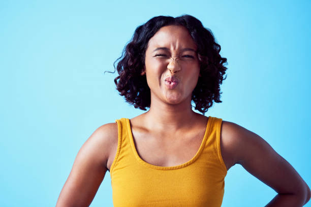 lustiges emoji-mädchen mit komischer nase und lippenausdruck auf ihrem gesicht auf einem studioblauen hintergrund. comedy junge und einzigartige frau mit stinke, ew oder verrücktem gesicht für ein humorvolles, buntes und menschliches porträt - disgust women african ethnicity human face stock-fotos und bilder