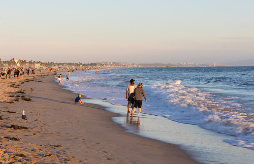 Santa Monica, CA - August 15 2022: Multi racial gay couple with their child on the beach in Santa Monica at sunset