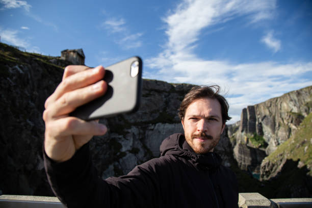 istock Caucasian man taking a selfie with an smartphone at Mizen Head Bridge, Ireland. Cliffs on the background 1420833078