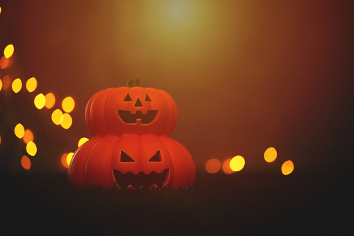 Halloween background with Jack o'lanterns and string lights under sunset