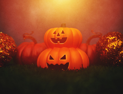 Halloween background with Jack o'lanterns and pumpkins under sunset