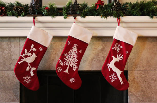 tres medias rojas de navidad sobre el manto de la chimenea - medias de navidad fotografías e imágenes de stock