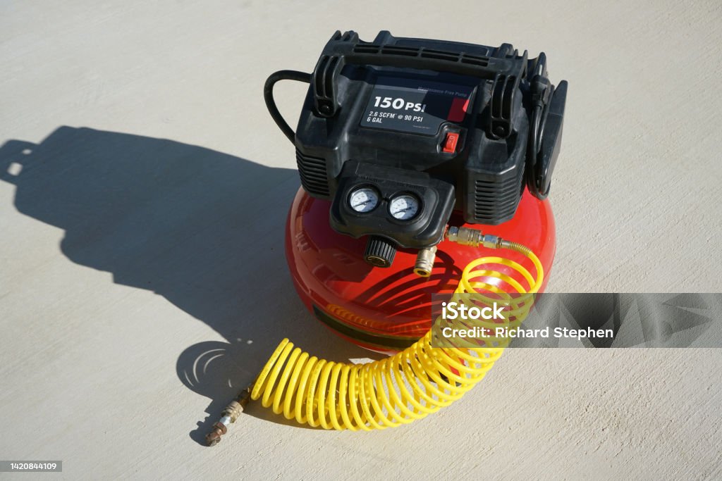Portable electric air compressor with coiled hose. A portable electric air compressor with coiled hose. Air Compressor Stock Photo