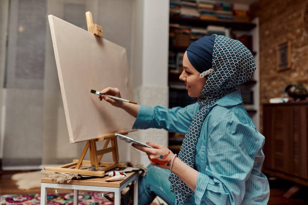 istock A woman in a hijab paints on canvas with a brush and tempera 1420844975