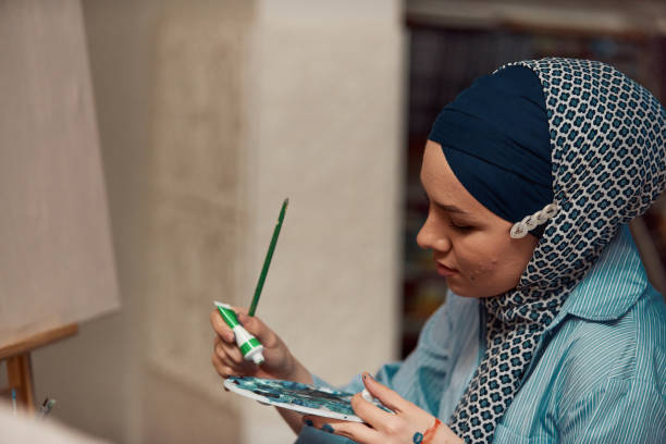 istock A woman in a hijab paints on canvas with a brush and tempera 1420845009