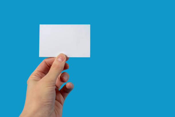 istock Human hand holding blank sheet of paper on blue background with blank space for text 1420845265