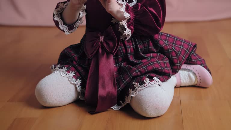 Cute little girl in an vintage burgundy dress is playing with a hair clip