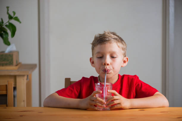 istock Cute boy drinking water through the drinking straw. Lifestyle portrait. 1420850618
