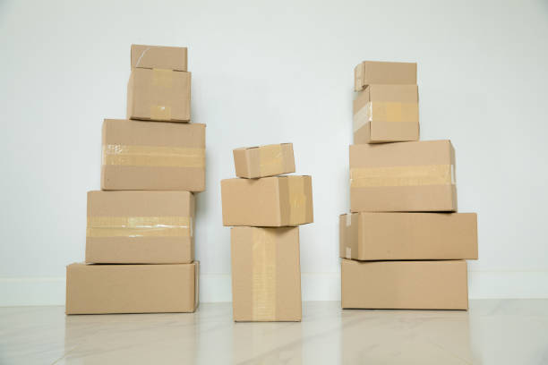 istock Stack of cardboard boxes for moving, Empty room with a white wall and cardboard boxes with unbranded barcode on the floor. Delivery of goods, shopping. Cardboard boxes on gray wall background. 1420863735