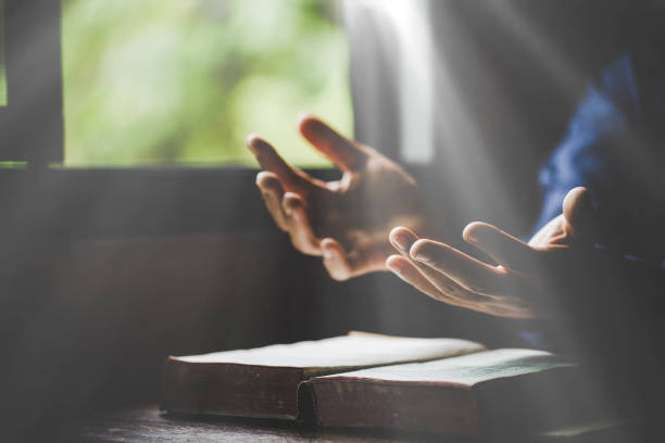 hand gefaltet im gebet zu gott auf dem buch der heiligen bibel im kirchlichen konzept für glaube, spiritualität und religion, frau betet am morgen auf der heiligen bibel. christlich-katholische frau hand mit bibelanbetung. - charmant stock-fotos und bilder