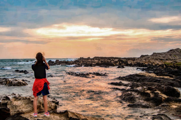 mädchen, das ein foto auf einem felsen am strand macht - activity asia atmosphere beach stock-fotos und bilder