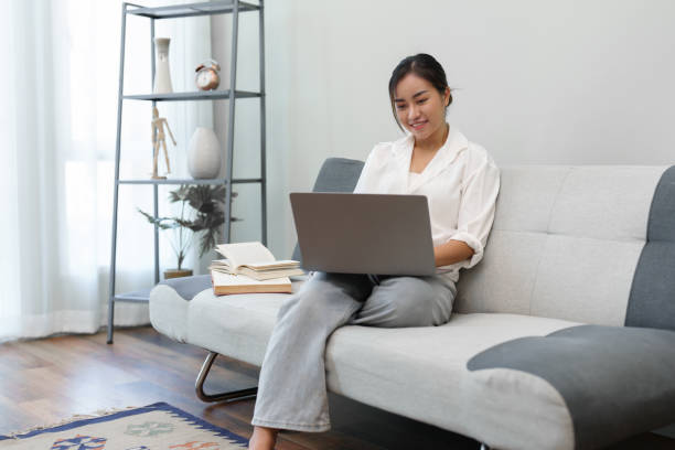 istock Portrait of a young Asian woman sitting on the sofa using a computer. 1420875316