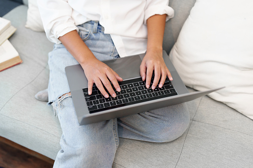 Portrait of a young Asian woman sitting on the sofa using a computer