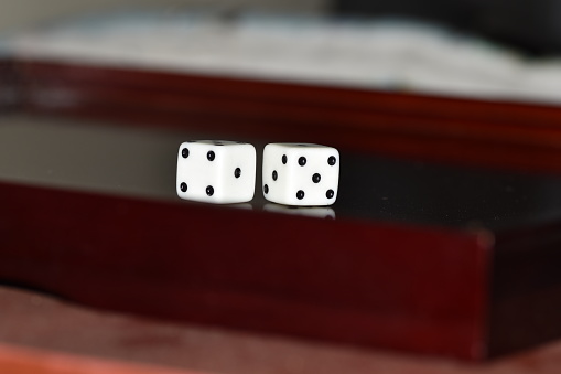 A close up view of dice being rolled on a craps table in a casino with slot machines in the background.  Please see my portfolio for other gambling related images. 