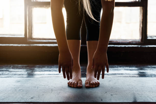 Close-up of a young woman getting ready for a sports workout. Reaches hands to the floor Close-up of a young woman getting ready for a sports workout. Reaches hands to the floor. High quality photo yoga studio photos stock pictures, royalty-free photos & images