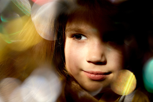 Close up dreamy face of pretty little child girl with xmas lights bokeh. Kid enjoy the holiday. Christmas and New Year concept. Happy, wishing, waiting. Merry Christmas and happy holidays!