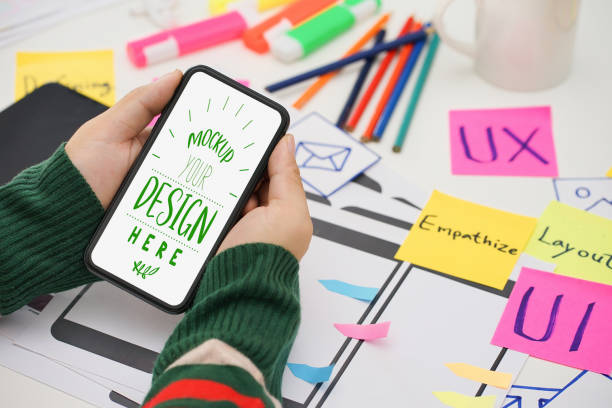 istock Creative top view photo of UX UI designer working space with mobile white screen mockup, white screen for graphic montage. 1420892724