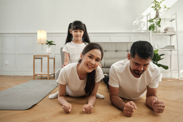 istock Asian Children tease their parents while exercise training in white living room. 1420896982