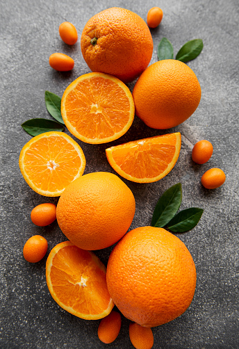 Fresh ripe oranges and  kumquat on dark concrete background