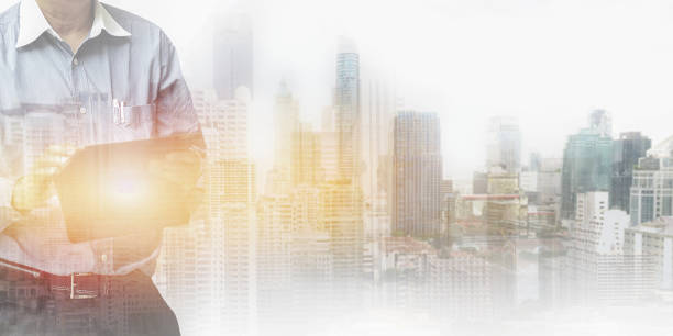 istock Double exposure image of business man working on tablet with bright light and modern buildings in urban big city background for business and industry advertising backdrop. 1420900263