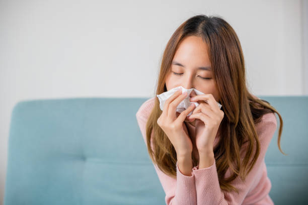 istock Ill Asian young woman cold covered with blanket sitting on sofa 1420904192
