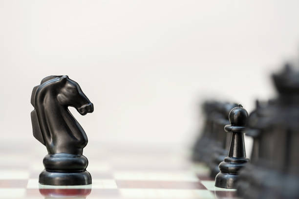 istock Black chess horse opposite black pieces on a chessboard 1420904233