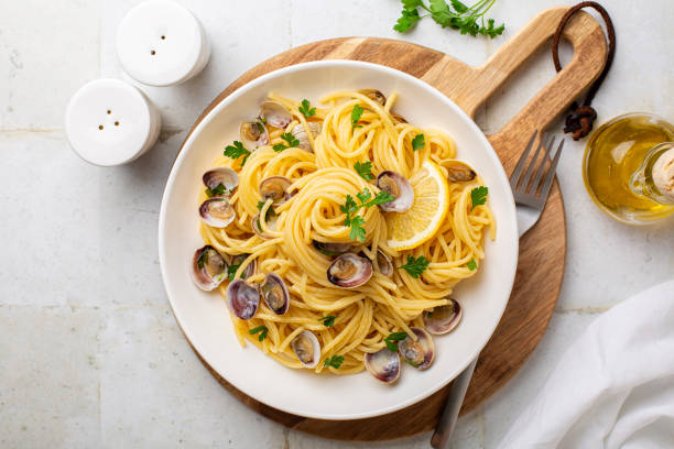 Italian pasta spaghetti with clams and lemon or Spaghetti alle vongole verace, cooked with oil, white wine, garlic, parsley. Top view. stock photo