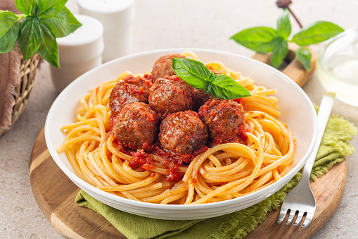 Spaghetti and beef Meatballs with tomato sauce in white dish on wooden rustic board, Italian-American food. Close-up.