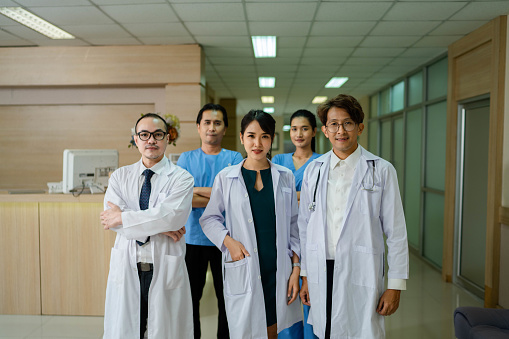 Portrait of group of diverse medical professionals brief meeting while walking in the hallway they are each wearing scrubs and focused on the conversation.