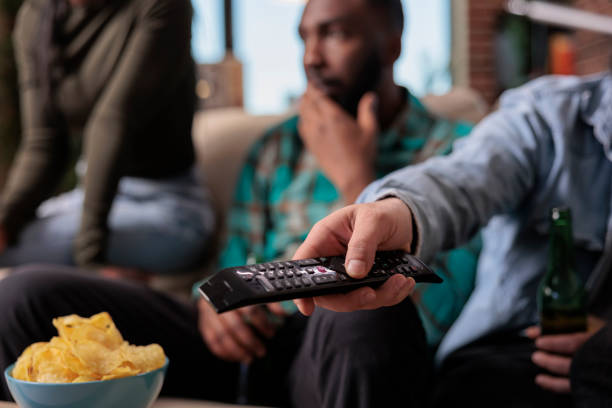 istock Young adult switching television channel programs with tv remote control 1420910787
