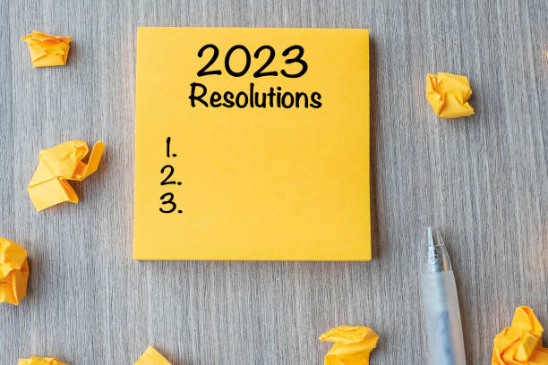 istock 2023 RESOLUTIONS word on yellow note with pen and crumbled paper on wooden table background. New start, Strategy and Goal concept 1420915183