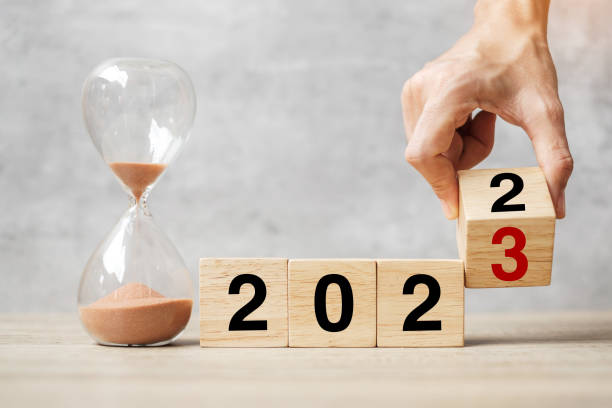 istock hand flipping block 2022 to 2023 text with hourglass on table. Resolution, time, plan, goal, motivation, reboot, countdown  and New Year holiday concepts 1420915275