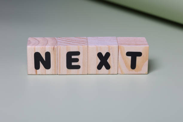 istock NEXT word on wooden block  on green background 1420917720