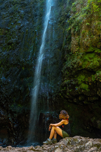 Joven irreconocible sentada en la cascada de la Levada do Caldeirao Verde, Queimadas, Madeira photo