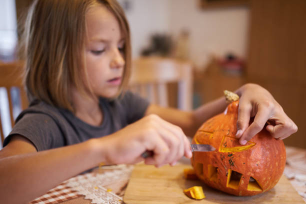 istock 8 year old boy carving Halloween pumpkin 1420920714