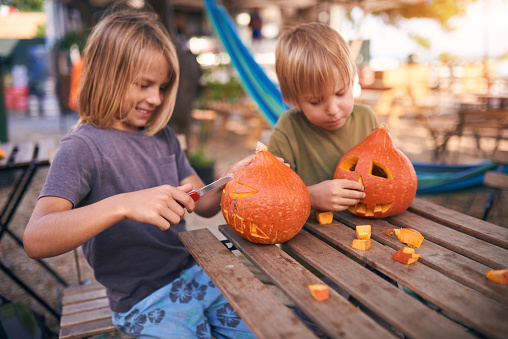 Young kids carving Halloween pumpkin outdoor