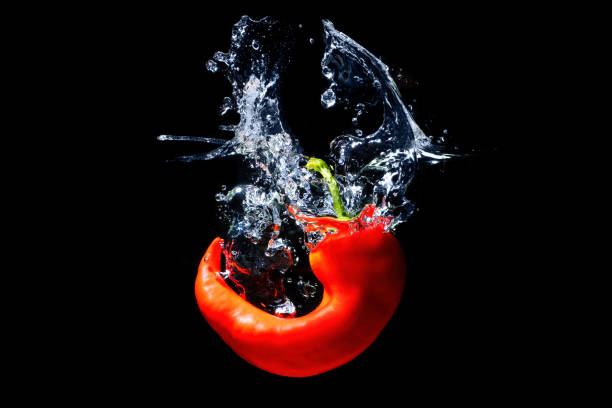 istock Curly chilli pepper splashing in water on black 1420920792