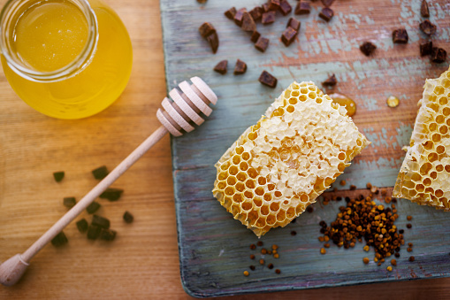 Honey background. Sweet honey in a glass jar, honeycombs, propolis and pollen on the table.