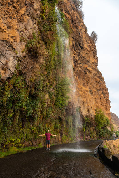 istock A young man looking at the waterfall that falls on the road called Anjos Waterfall, Madeira 1420921803