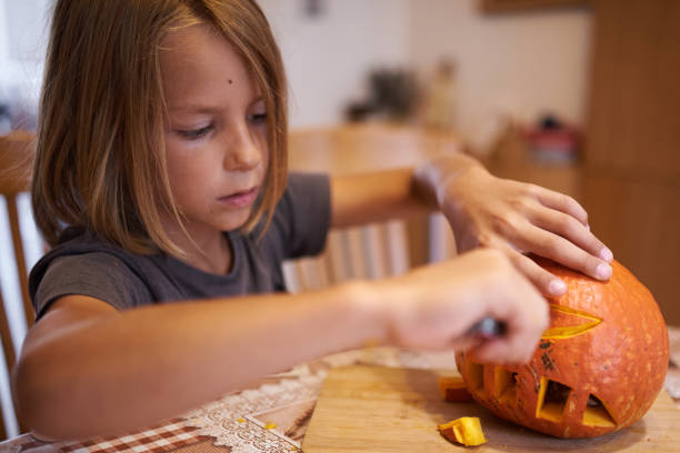 istock 8 year old boy carving Halloween pumpkin 1420924376