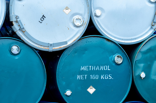 Old chemical barrels. Stack of blue methanol or methyl alcohol drum. Steel chemical tank. Toxic waste. Chemical barrel with toxic warning symbol. Industrial waste in drum. Hazard waste storage.